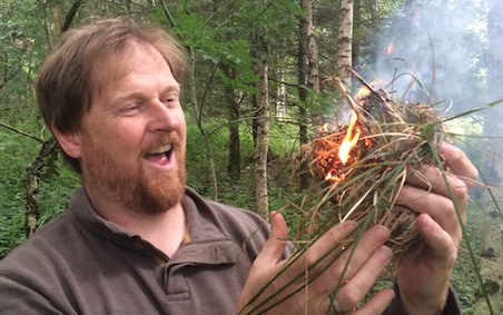 Malcolm firemaking in woods Malcolm holding a tinder nest and fire in his hands